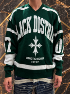 Maglione verde Black District indossato, collo a V e dettagli avorio su fondo nero e oro, senza volto