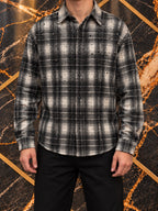 Camicia a quadri grigio e nero con applicazioni, indossata, inquadratura senza volto su marmo nero e oro — immagine rielaborata