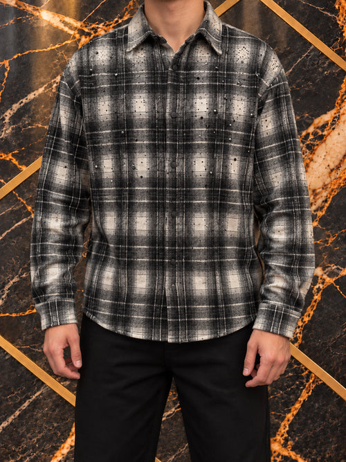 Camicia a quadri grigio e nero con applicazioni, indossata, inquadratura senza volto su marmo nero e oro — immagine rielaborata
