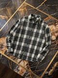 Camicia grigia e nera a quadri con applicazioni, fotografia reale del capo disposto in piano