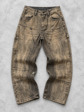 Jeans marrone con schizzi chiari a contrasto, vista frontale in piano su fondo grigio