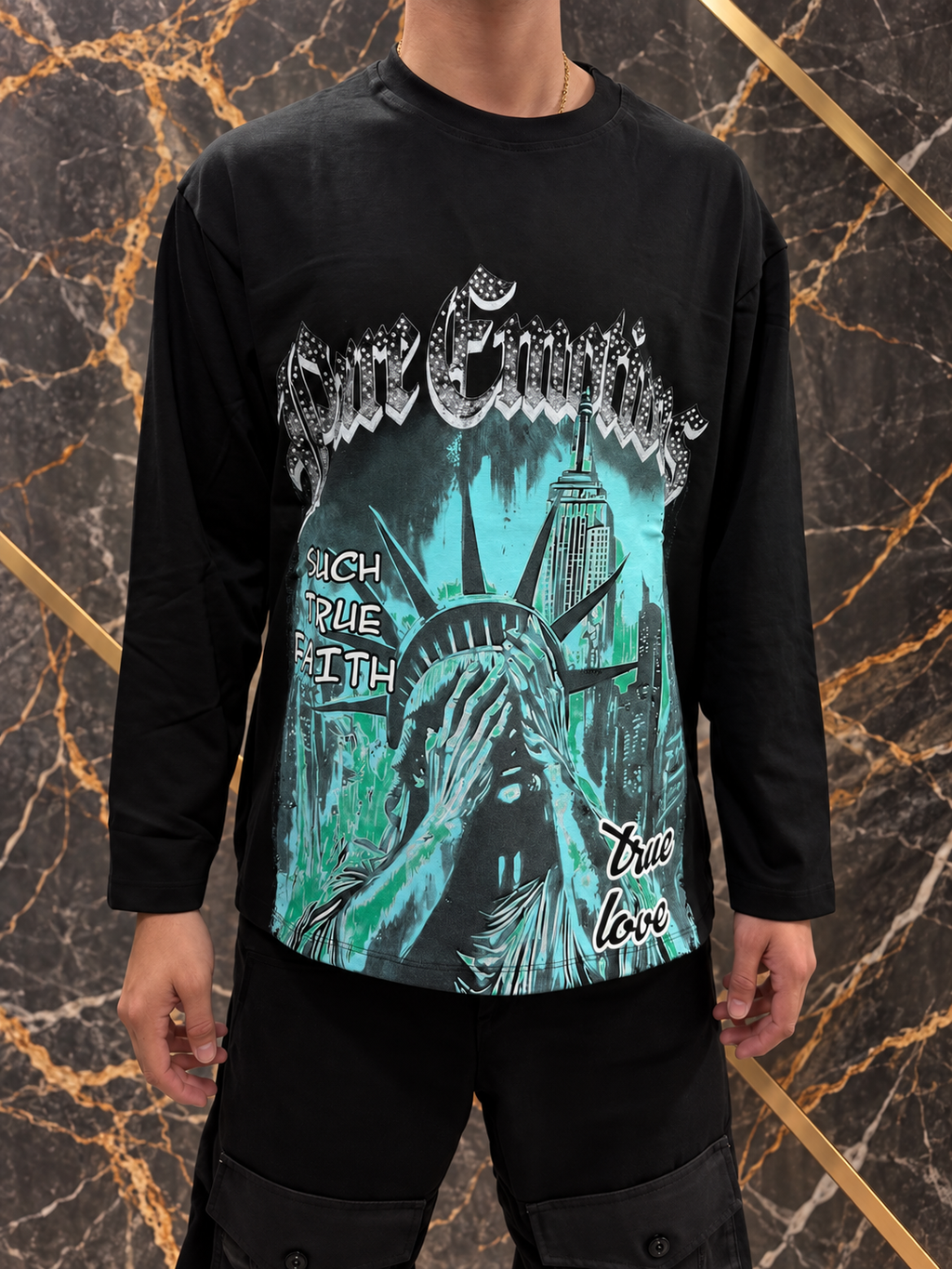 Maglia nera New York indossata, stampa turchese e inquadratura senza volto su fondo nero e oro